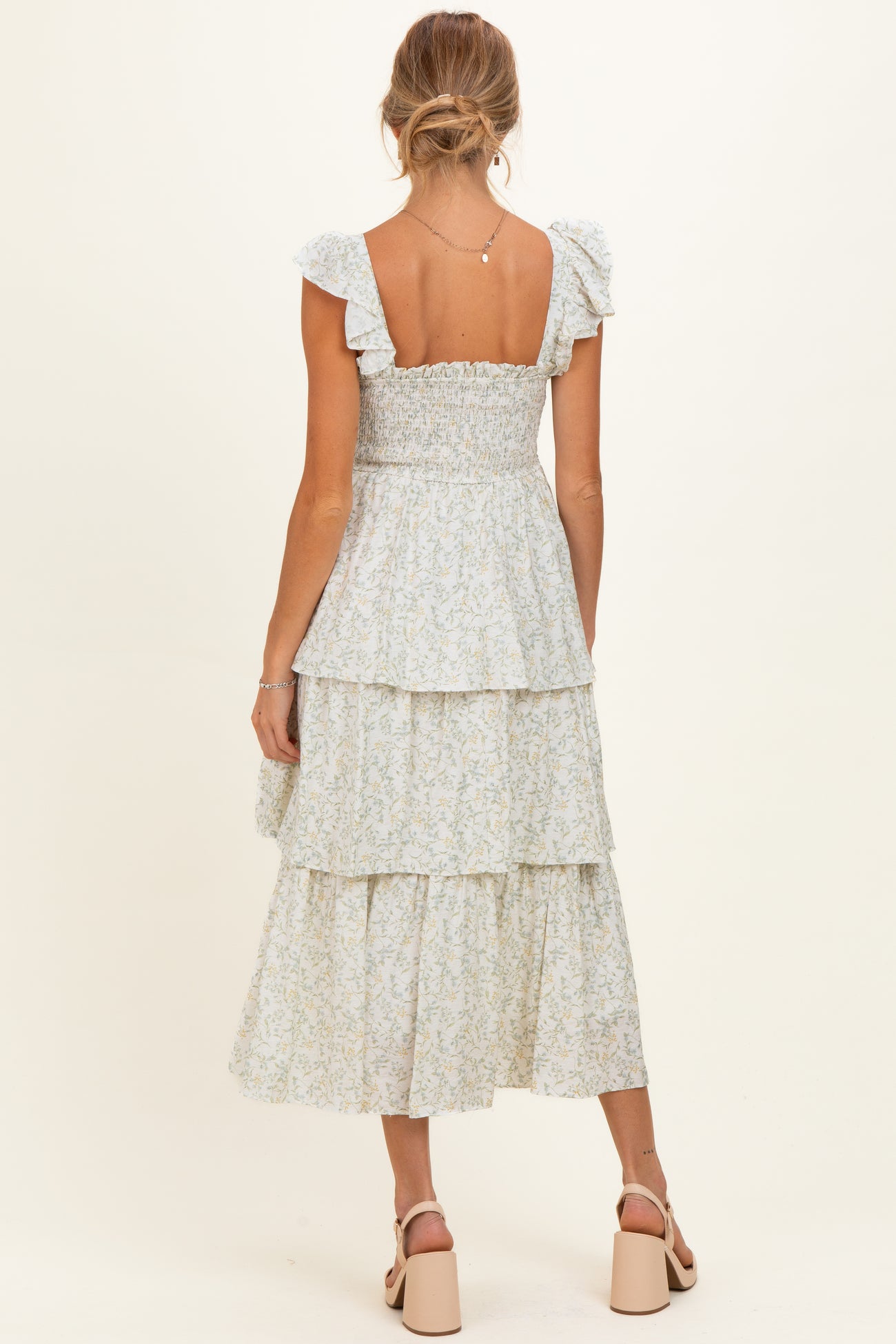 woman wearing a light blue floral maternity dress with ruffled straps and a tiered skirt, showing off her baby bump