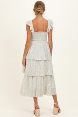 woman wearing a light blue floral maternity dress with ruffled straps and a tiered skirt, showing off her baby bump