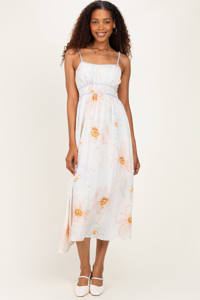 woman wearing a light blue floral maxi dress with thin straps and a fitted bodice, standing with a smile