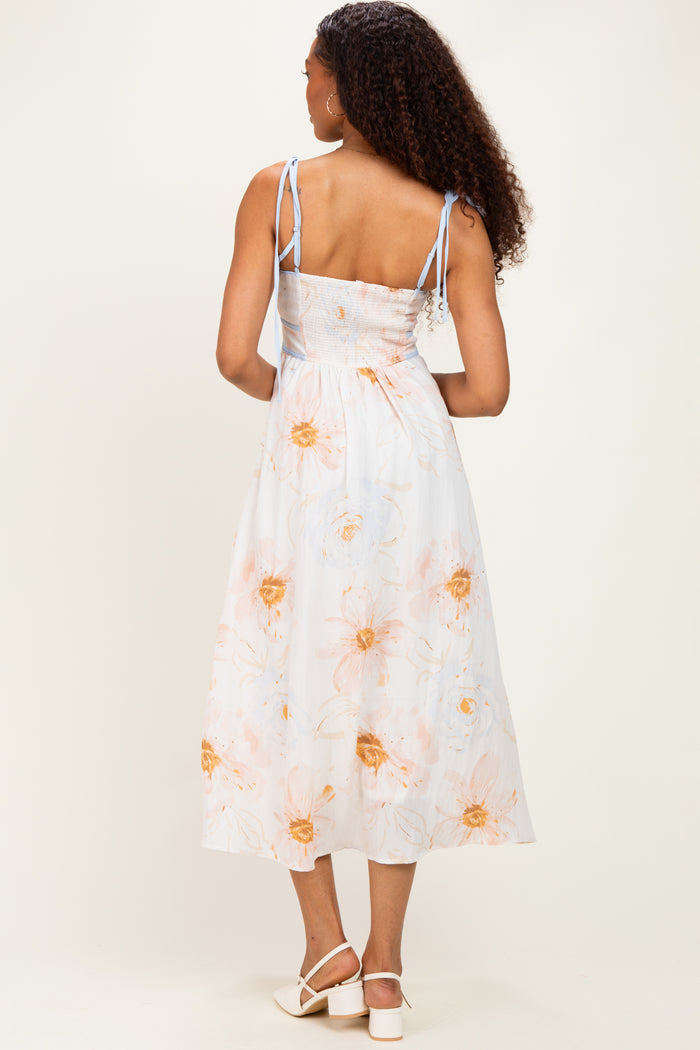 woman wearing a back view of a light blue floral midi dress with smocked bodice and adjustable straps