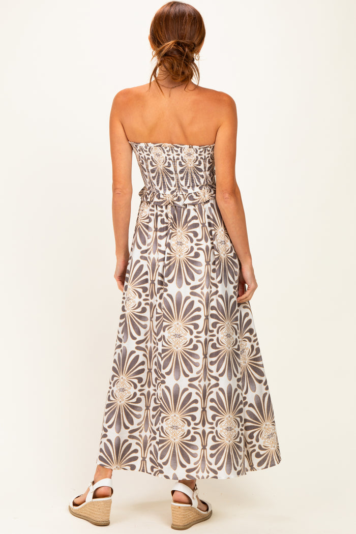 woman wearing a strapless maxi dress with a floral pattern in shades of gray and beige