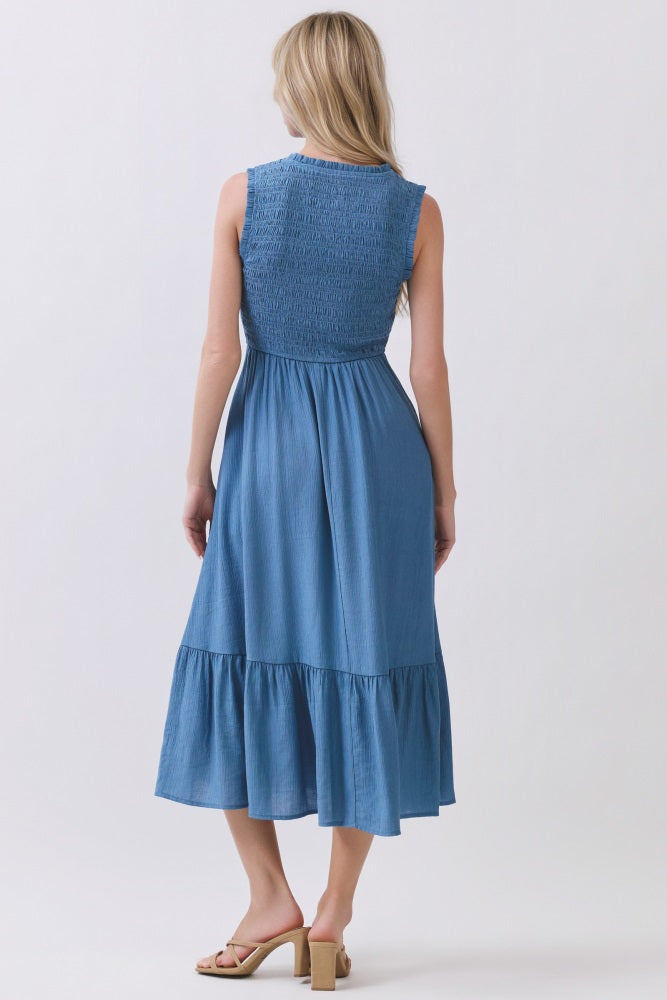 woman wearing a sleeveless blue midi dress with a smocked bodice and a tiered ruffled hem