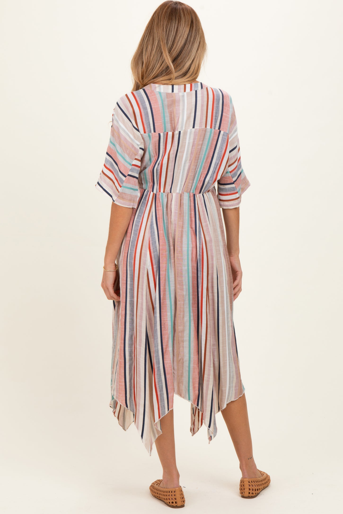 woman wearing a striped maternity dress with an asymmetrical hem and short sleeves, showing a relaxed fit from the back