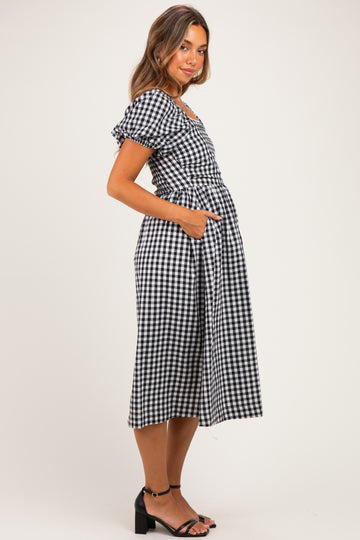 woman wearing a black and white checked maternity dress with puff sleeves and pockets