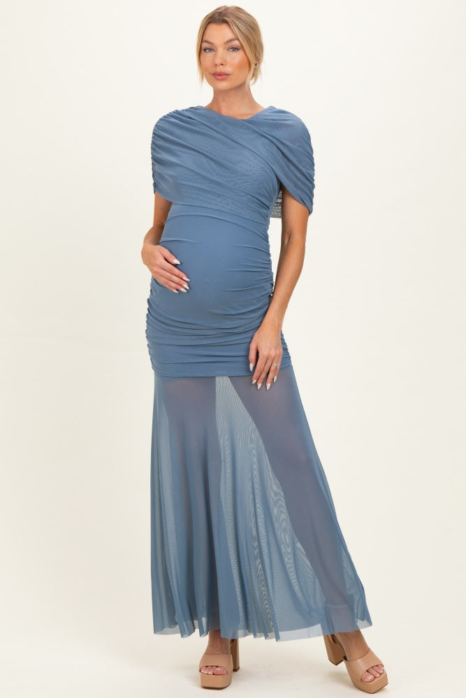 woman wearing a blue maternity dress with ruched bodice and flowy sheer skirt, holding her baby bump
