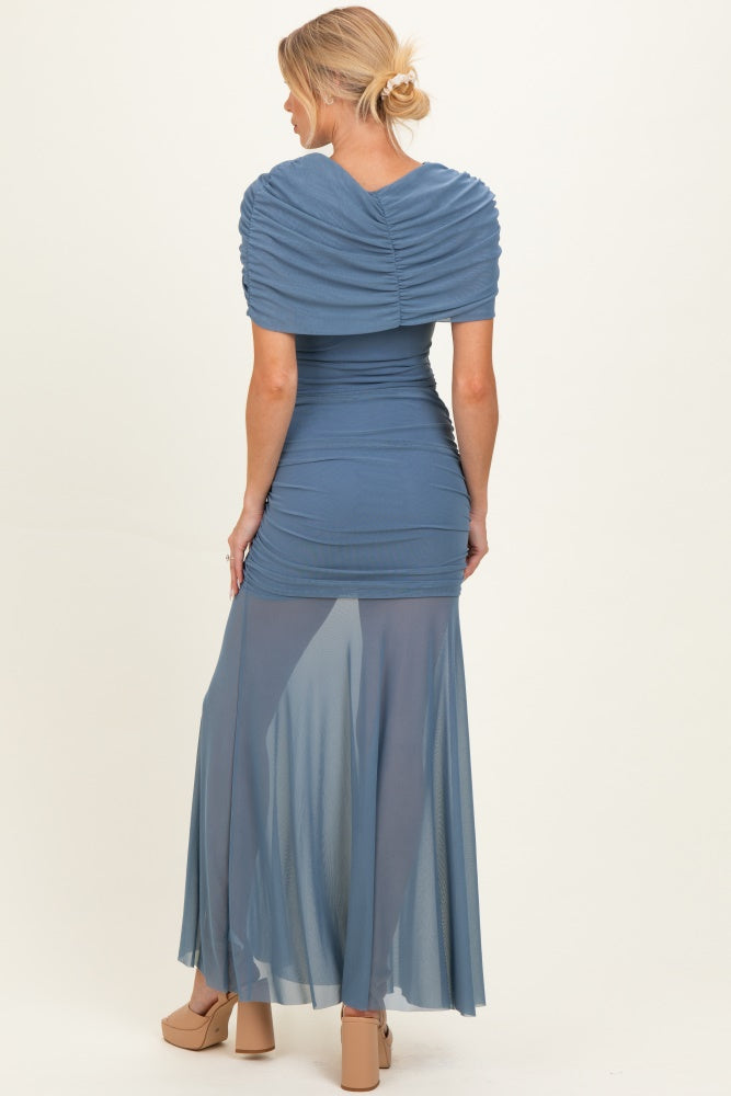 woman wearing a blue maternity dress with ruched top and sheer maxi skirt, showing a baby bump