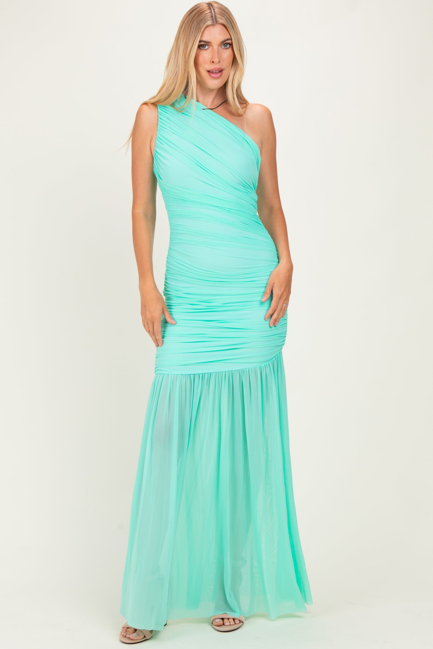 woman wearing a mint green one-shoulder evening gown with ruched details and a flowing skirt