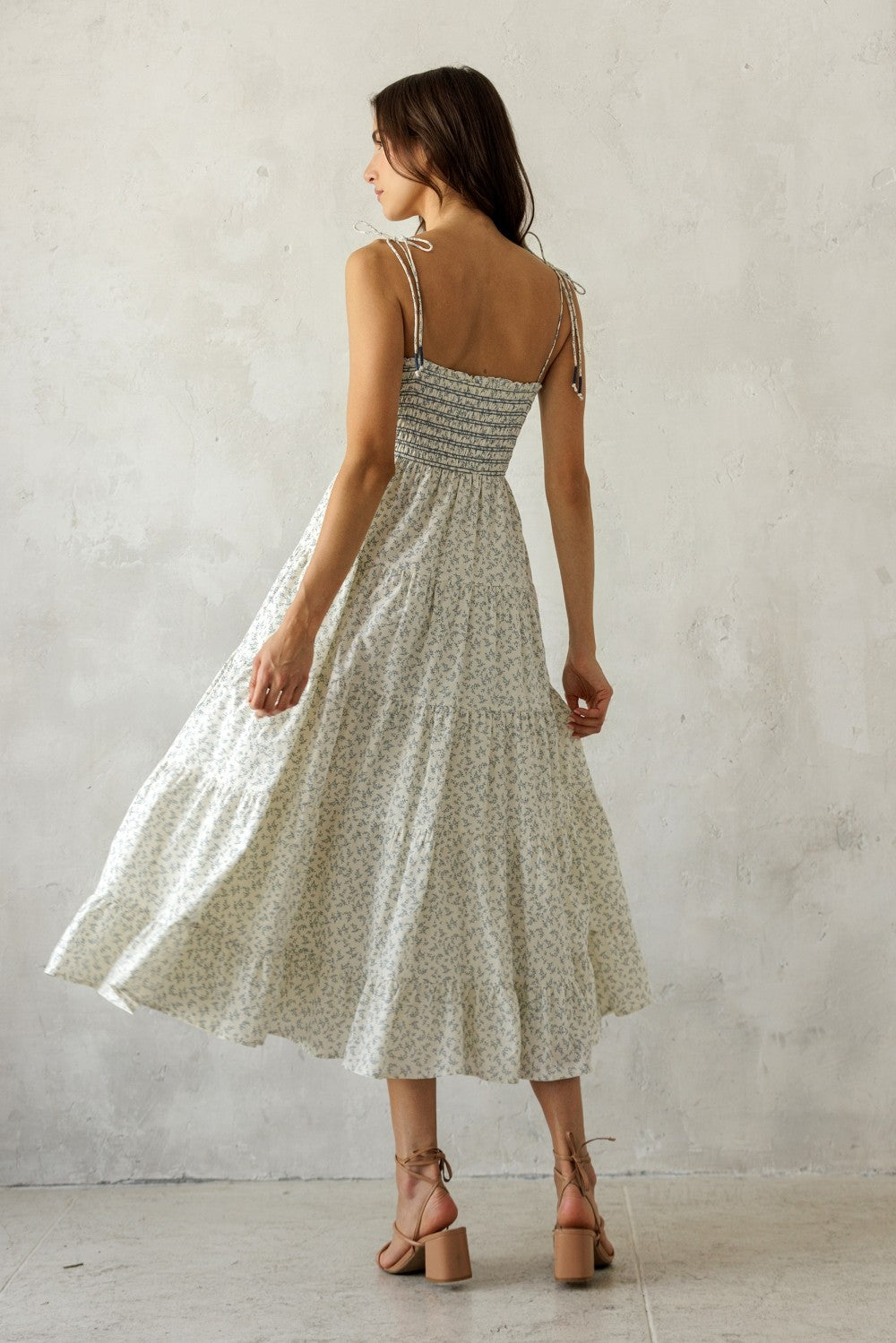 woman wearing a white floral maxi dress with adjustable tie straps, showing a smocked back detail