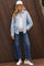 woman wearing a light blue striped maternity shirt and wide-leg jeans, showing her baby bump, styled with a cap and sneakers