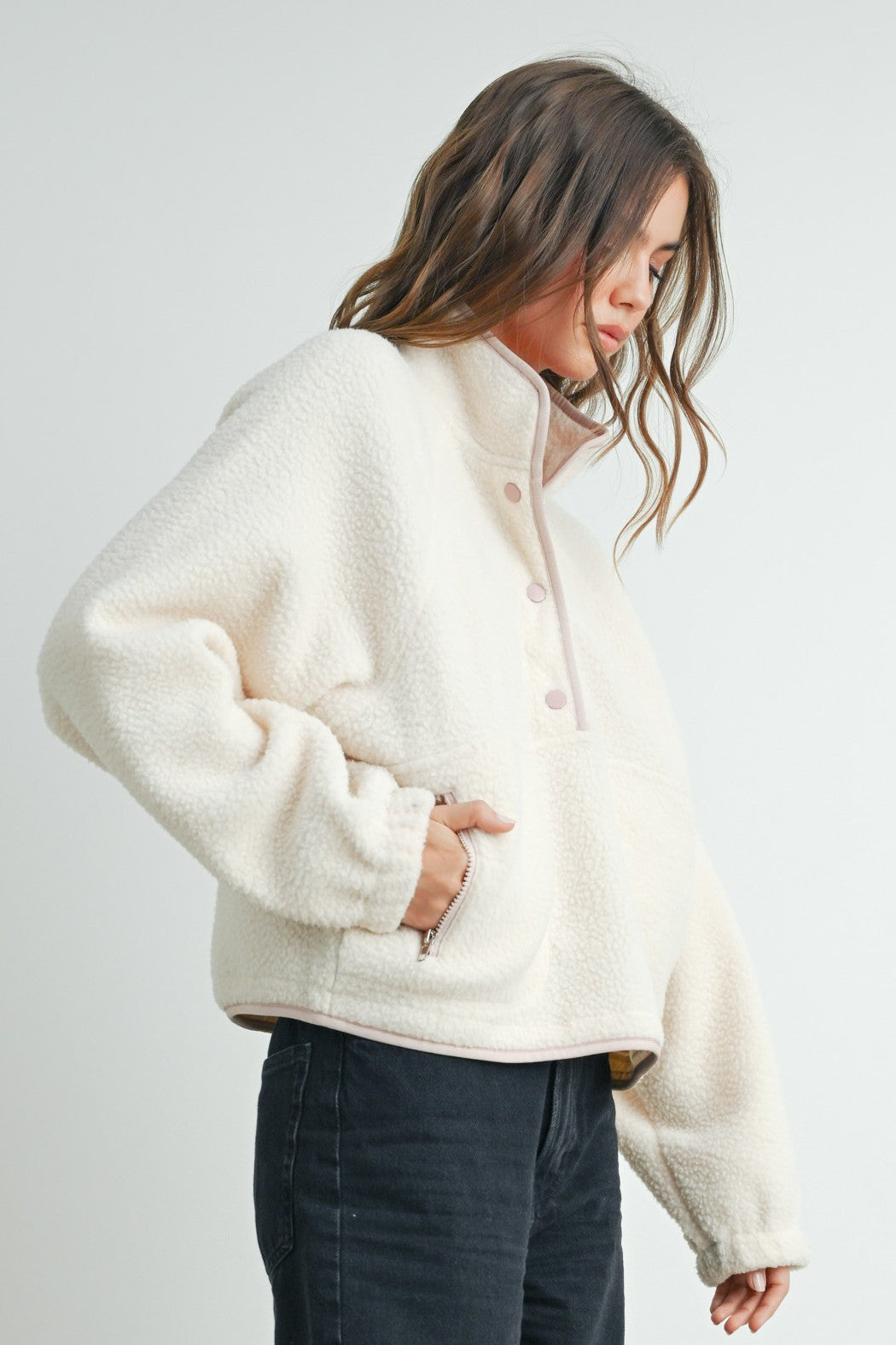 woman wearing a cream-colored fleece pullover jacket with a half-zip and pink details