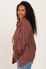 woman wearing a brown checkered maternity shirt and holding her baby bump