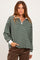woman wearing a dark green and white striped long sleeve quarter zip top with a relaxed fit and white collar