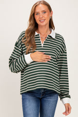 woman wearing a green and white striped maternity pullover with a half zipper, holding her baby bump