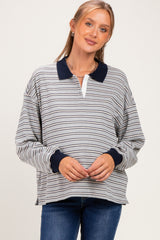 woman wearing a gray and navy striped maternity pullover with a polo collar and long sleeves, showing her baby bump
