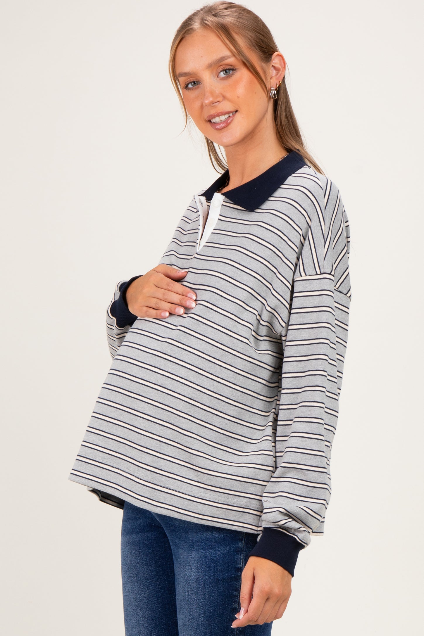 woman wearing a striped maternity long sleeve polo shirt and holding her baby bump
