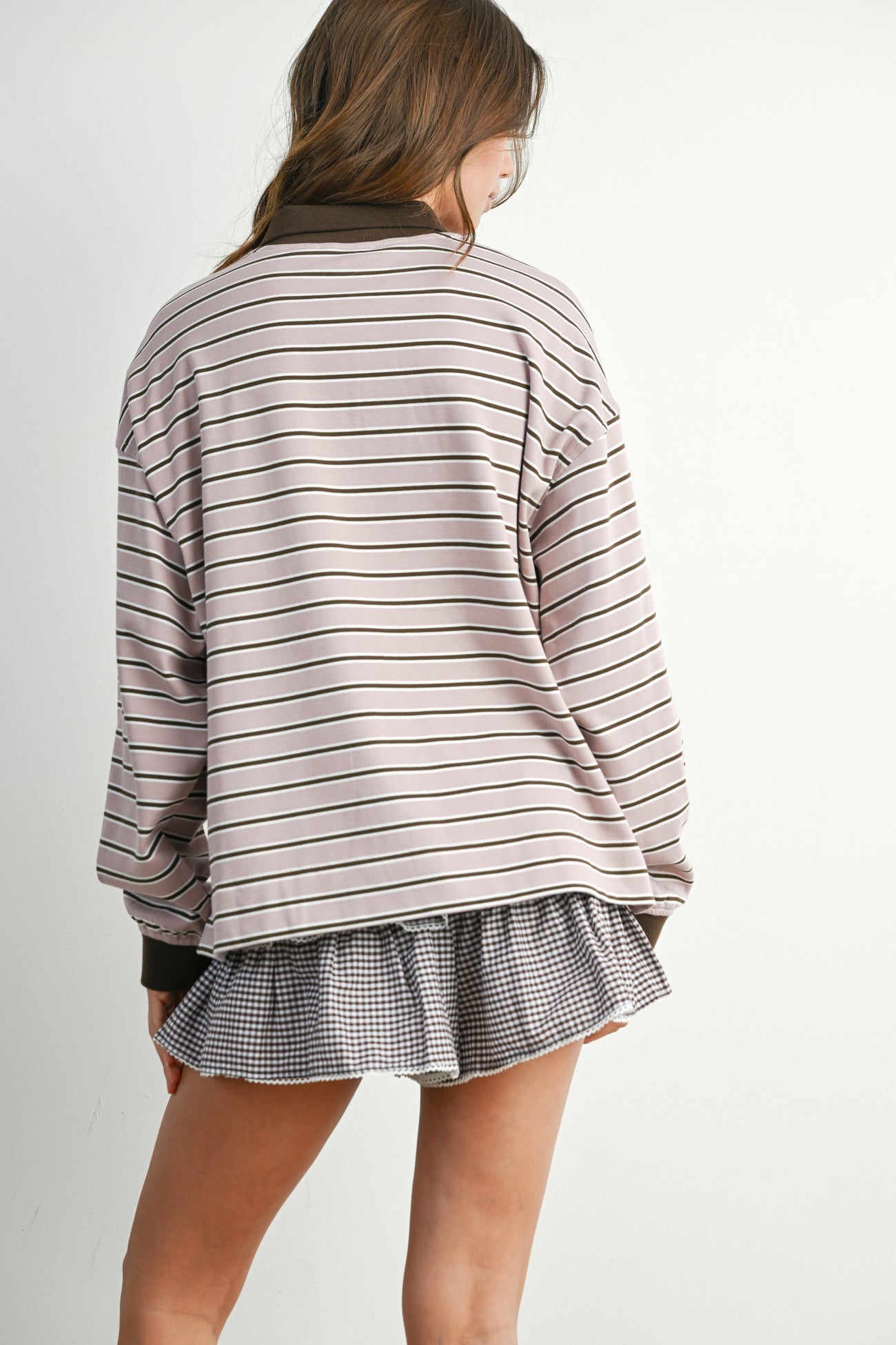 woman wearing a striped oversized sweatshirt with long sleeves and a ruffled checkered skirt