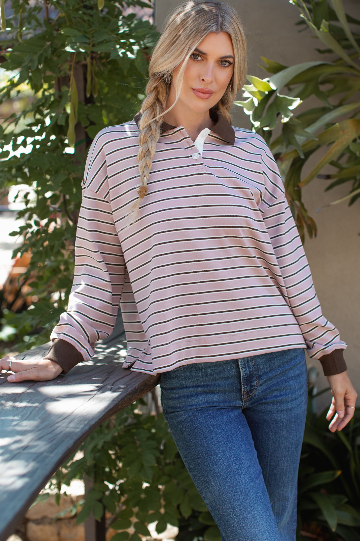 woman wearing a pink and brown striped long sleeve polo shirt with a relaxed fit and blue jeans