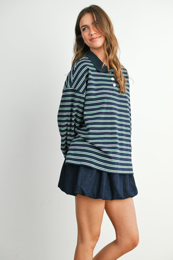 woman wearing a navy blue striped long sleeve polo shirt and a dark blue flared skirt