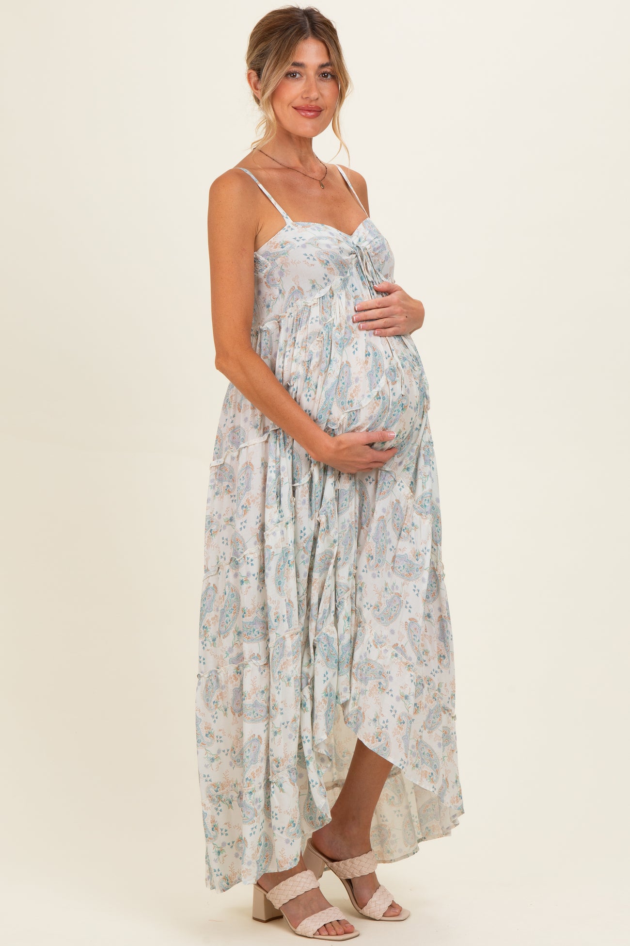 woman wearing a light floral maternity maxi dress and holding her baby bump