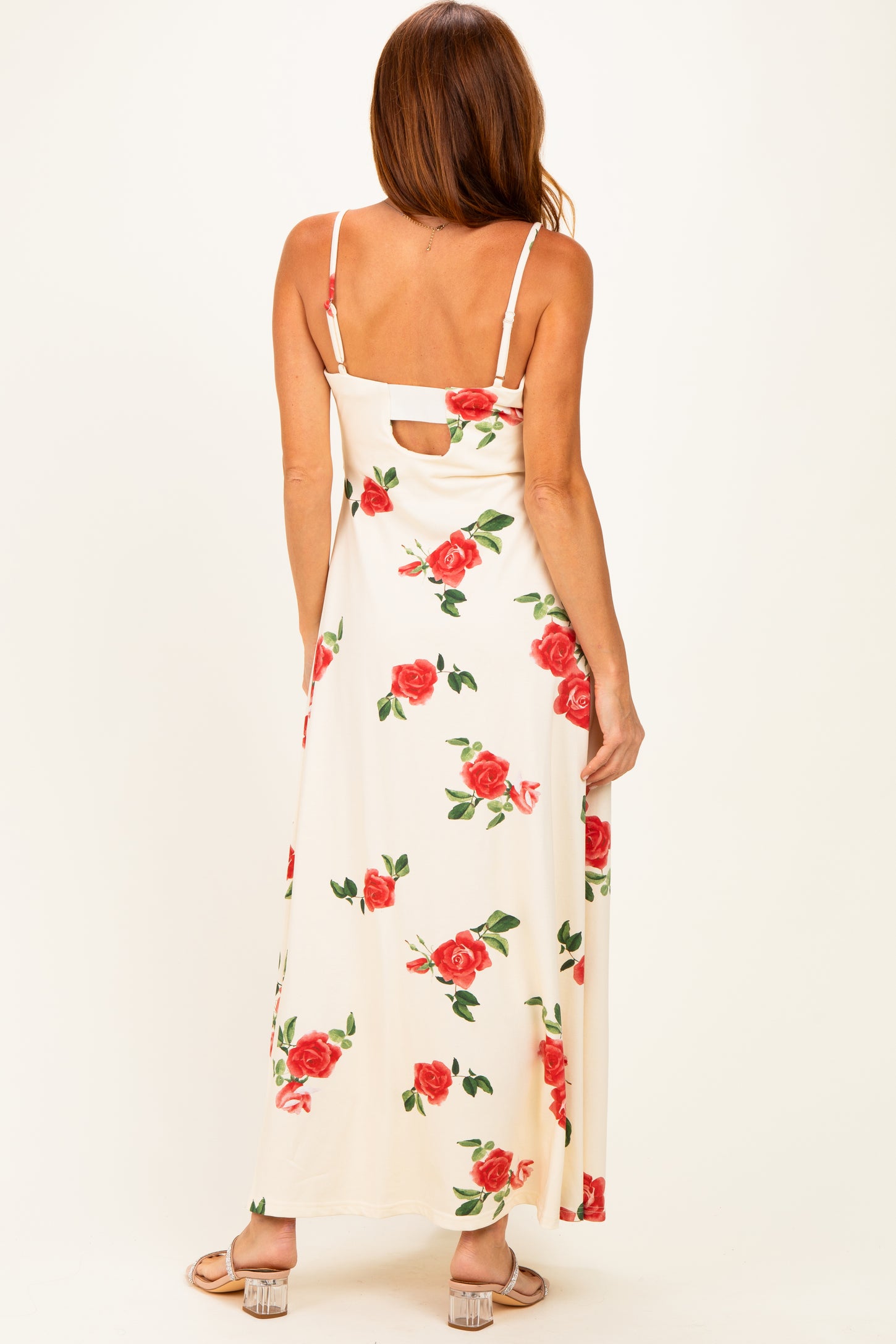woman wearing a floral maxi dress with a keyhole back detail, shown from the back with red roses on a light background