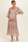 woman wearing a floral print maternity maxi dress with puff sleeves and a fitted bodice, holding her baby bump