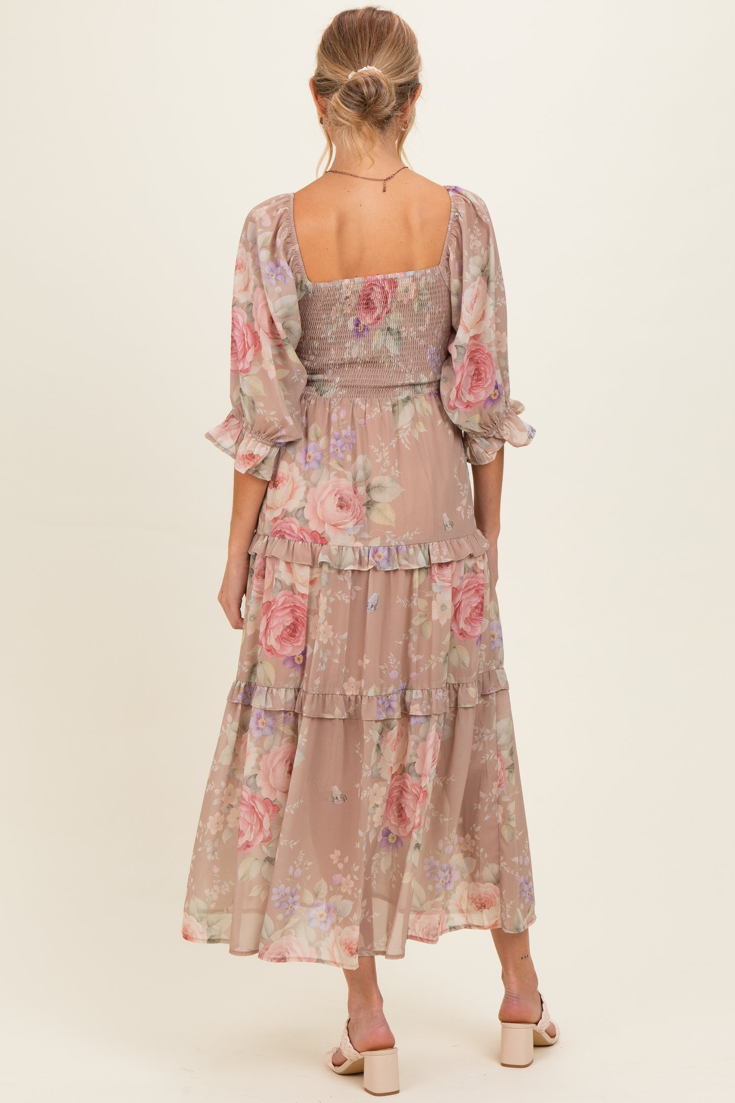 woman wearing a floral patterned maternity maxi dress with a smocked bodice and tiered skirt, showing a baby bump from behind