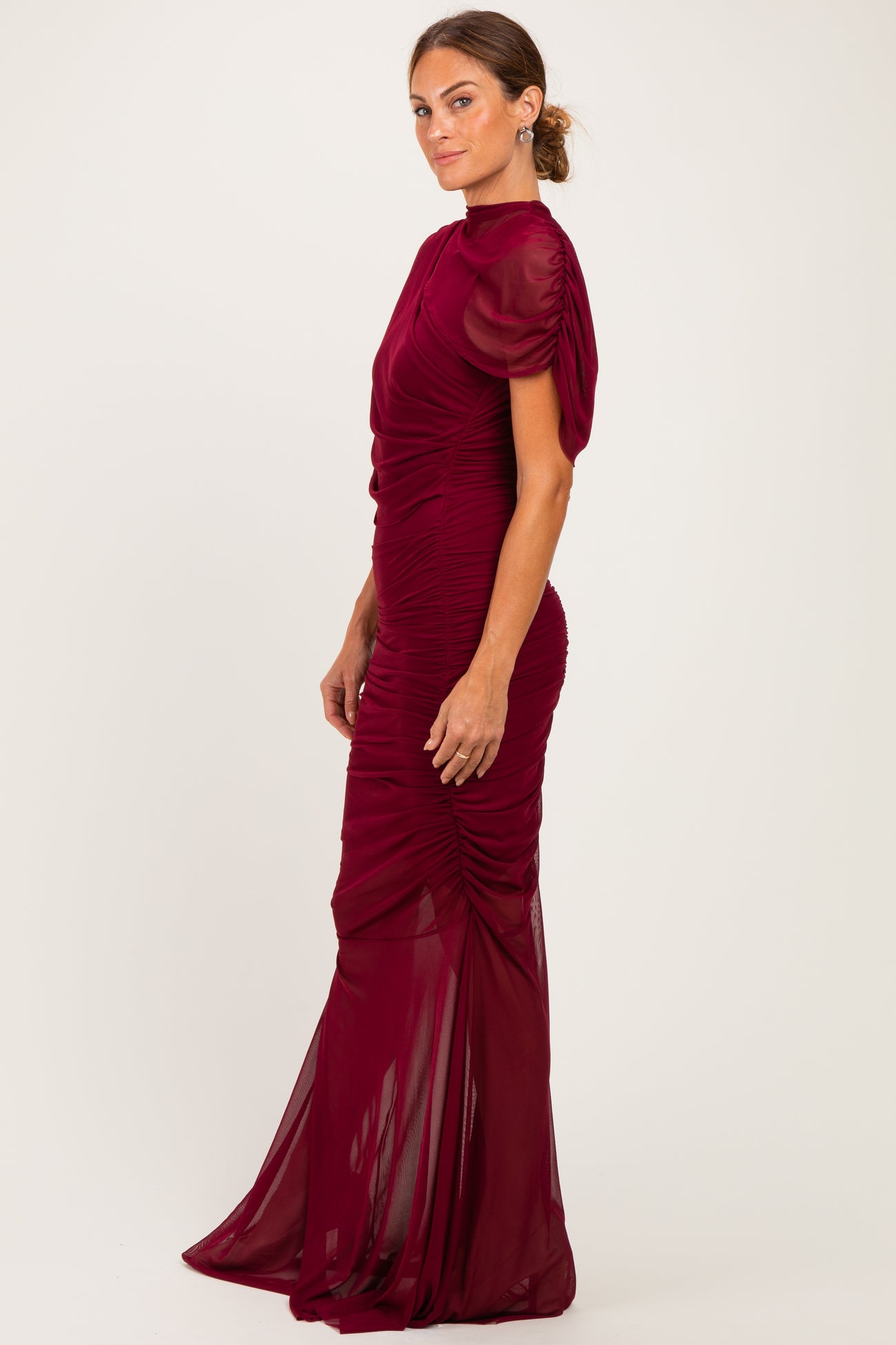 woman wearing a burgundy ruched evening gown with short puff sleeves and a fitted silhouette