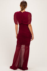woman wearing a burgundy ruched evening gown with puff sleeves and a fitted silhouette, seen from the back