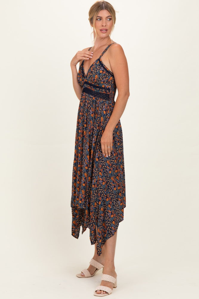 woman wearing a navy blue floral maxi dress with a high-low hemline and thin straps, standing in profile