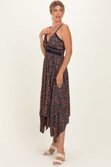 woman wearing a navy blue floral maxi dress with a high-low hemline and thin straps, standing in profile