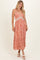 woman wearing a rust floral print maxi dress with a crochet detail, standing with one hand on her hip
