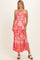woman wearing a coral strapless maxi dress with a floral pattern and a fitted bodice, standing in a neutral background