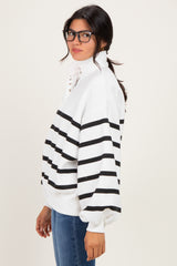 woman wearing a white and black striped pullover sweatshirt with a high collar and button details, styled with blue jeans
