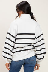 woman wearing a white and black striped oversized sweatshirt with a high collar and balloon sleeves