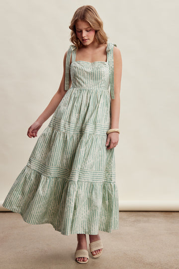 woman wearing a green and white striped maxi dress with tie straps and tiered skirt