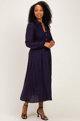 woman wearing a navy blue long sleeve dress with red polka dots and a button-down front, paired with black strappy heels