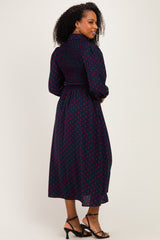 woman wearing a navy blue mid-length dress with red polka dots and a smocked back detail