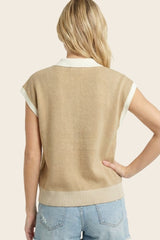 woman wearing a tan short sleeve sweater with a white collar and ribbed hem, seen from the back
