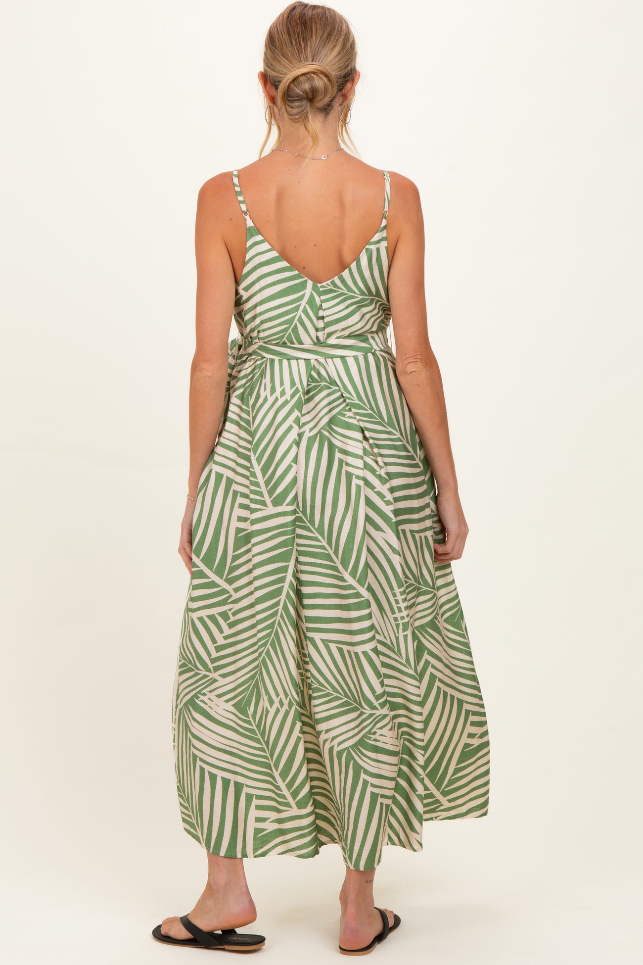 woman wearing a green and white striped maternity maxi dress with a back tie detail and adjustable straps