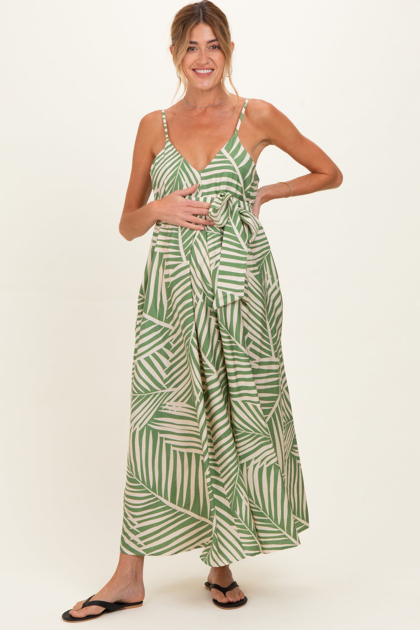 woman wearing a green and white striped maternity maxi dress with a tie waist and holding her baby bump
