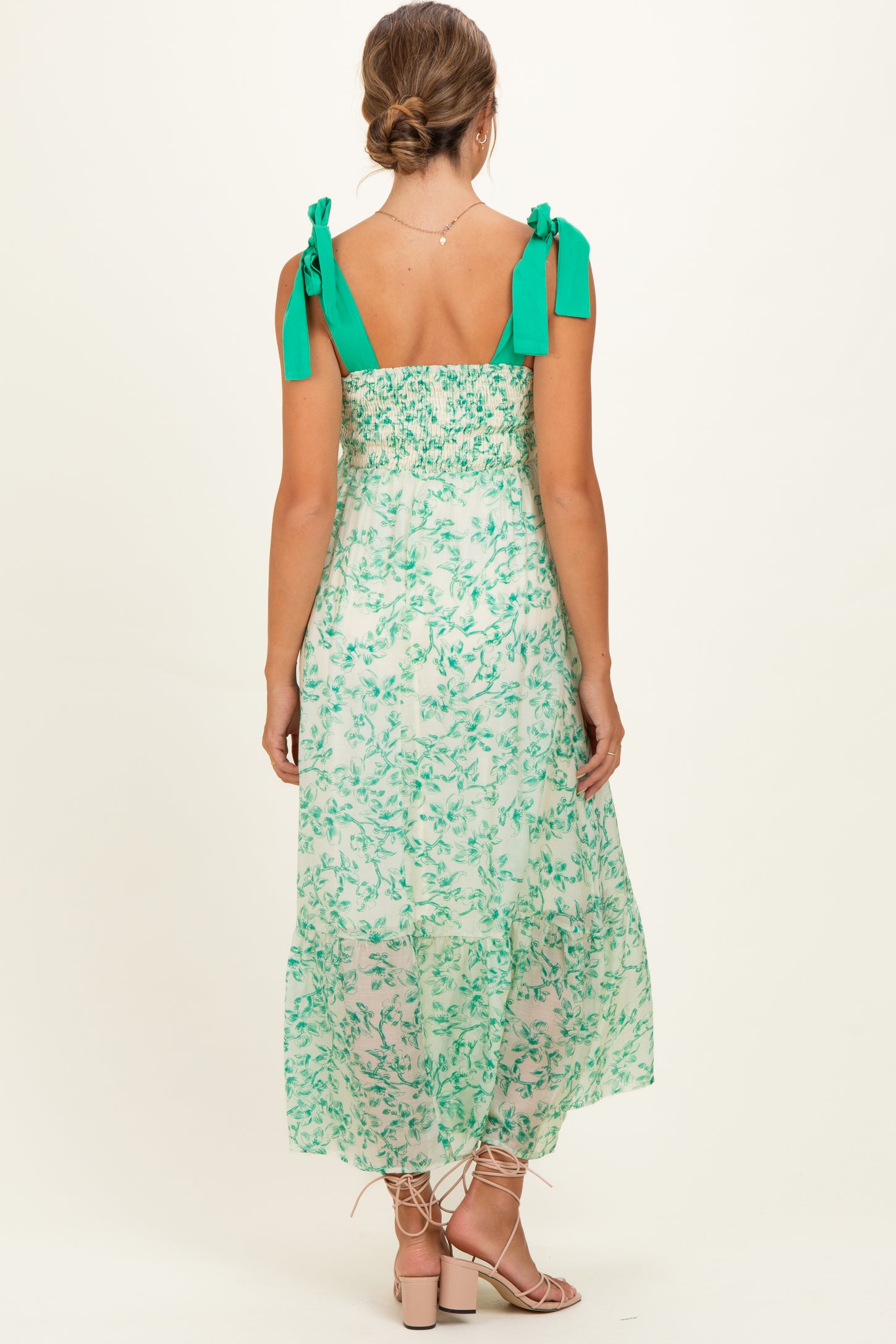 woman wearing a green floral maternity maxi dress with tie straps and a smocked back.