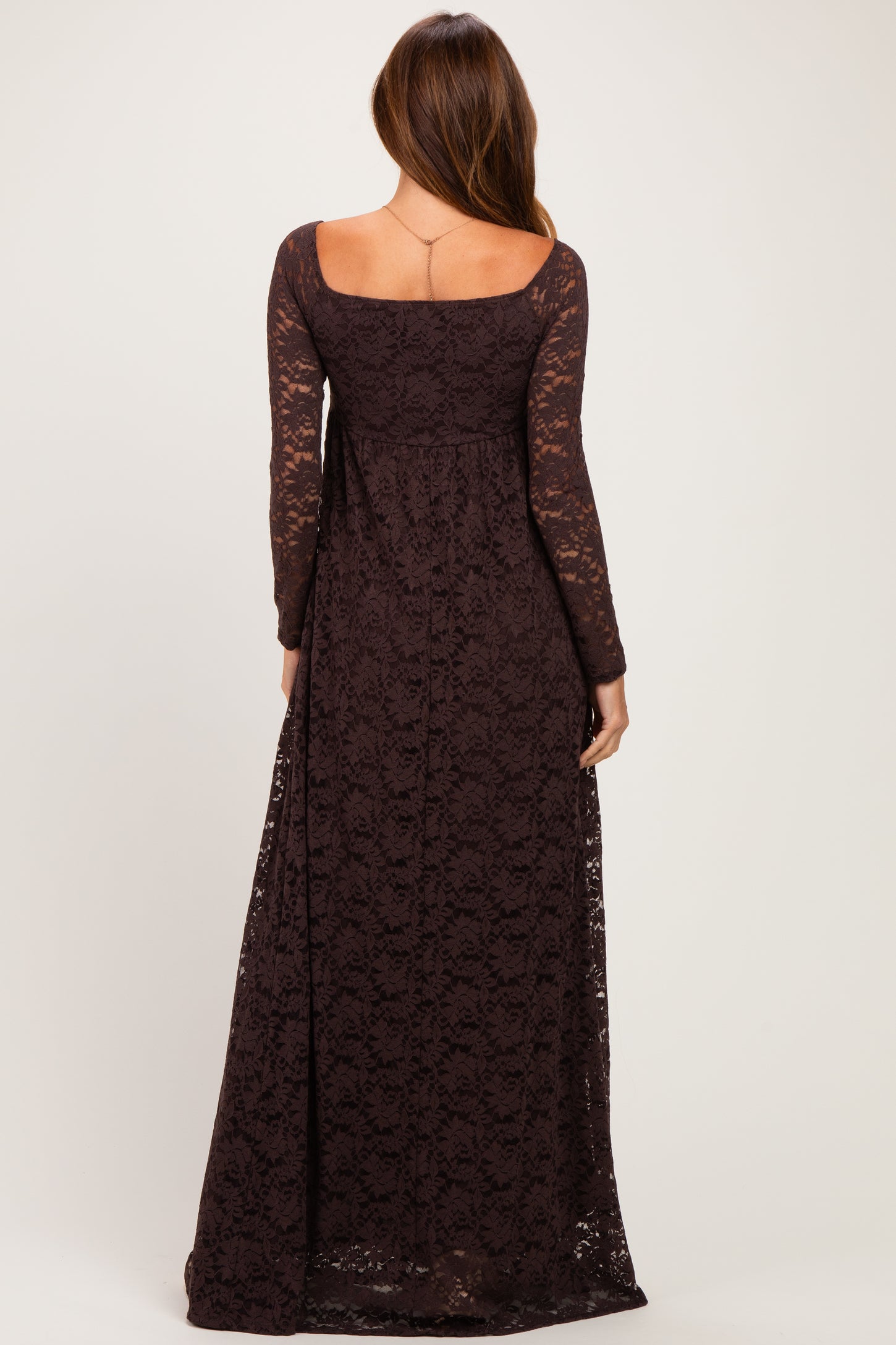 woman wearing a long sleeve dark brown lace maxi dress with a scooped back and flowing silhouette