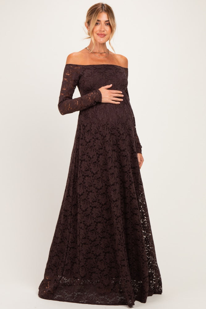 woman wearing a dark brown off-the-shoulder lace maternity gown and holding her baby bump
