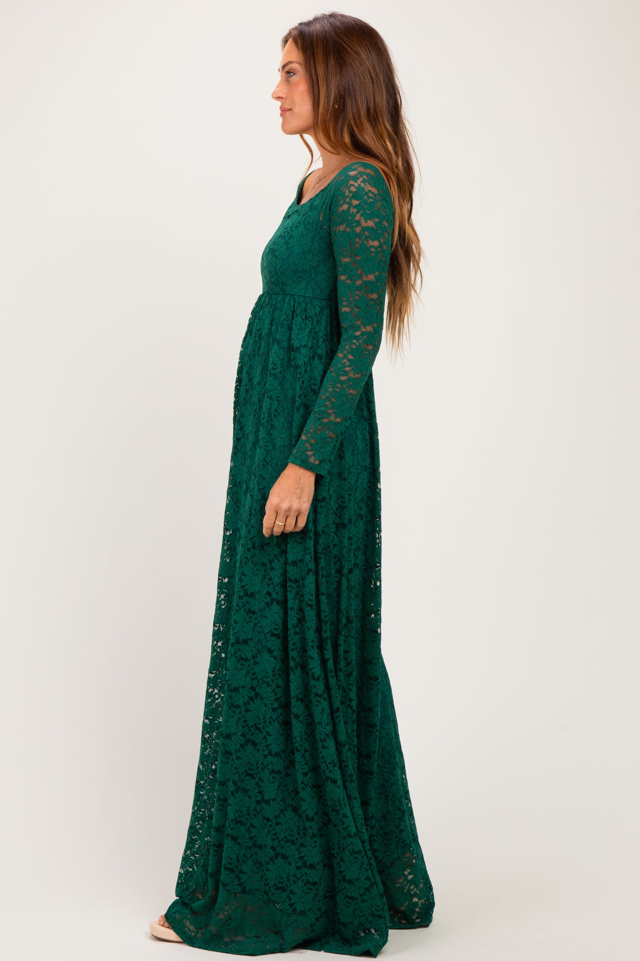 woman wearing a long sleeve dark green lace maxi dress standing in profile