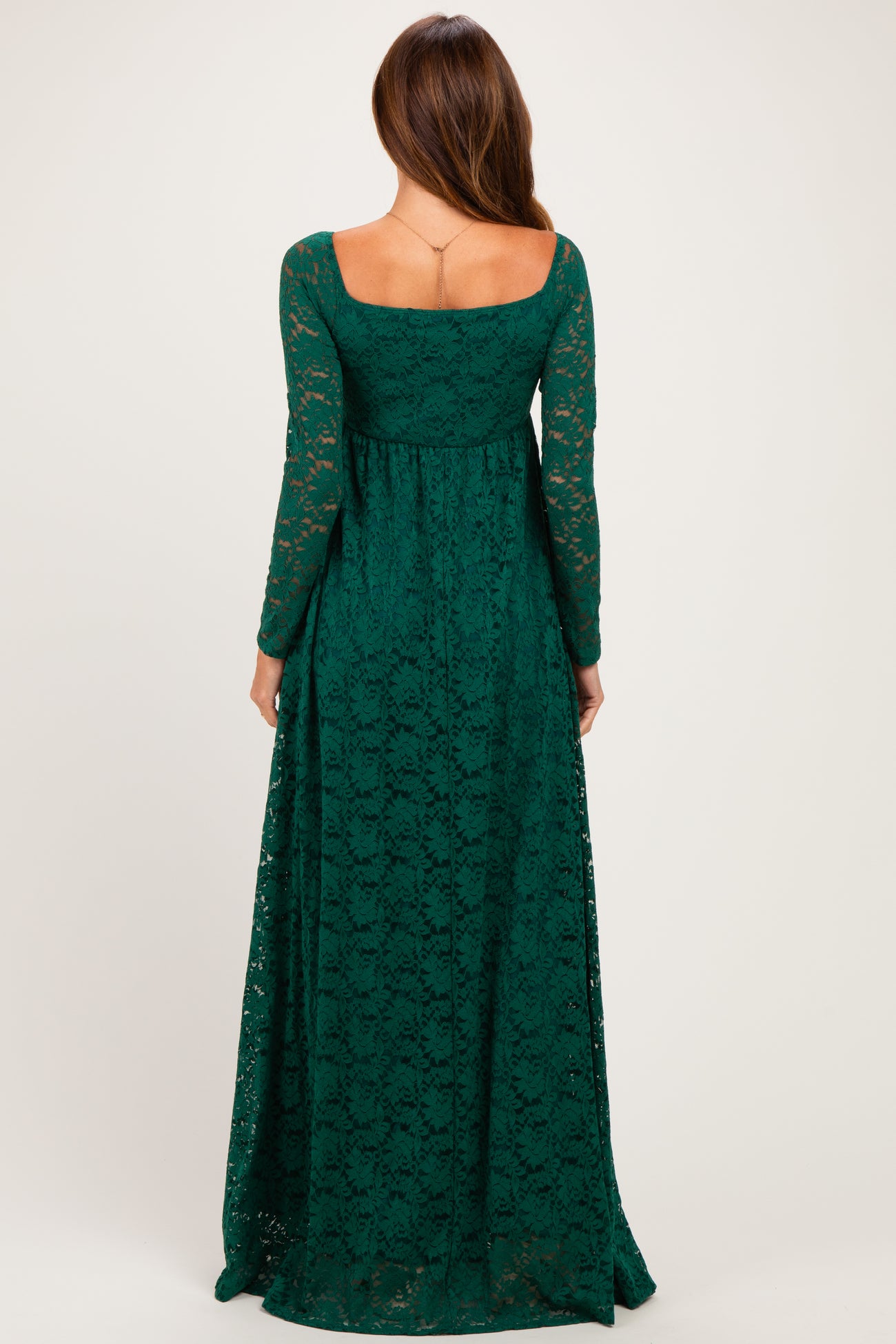 woman wearing a long sleeve dark green lace maxi dress with a fitted bodice and flared skirt, shown from the back
