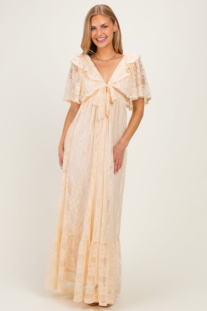 woman wearing a light peach lace maxi dress with a tie front and ruffled sleeves