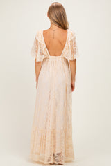 woman wearing a backless sheer lace maxi dress with flutter sleeves and a tiered hem