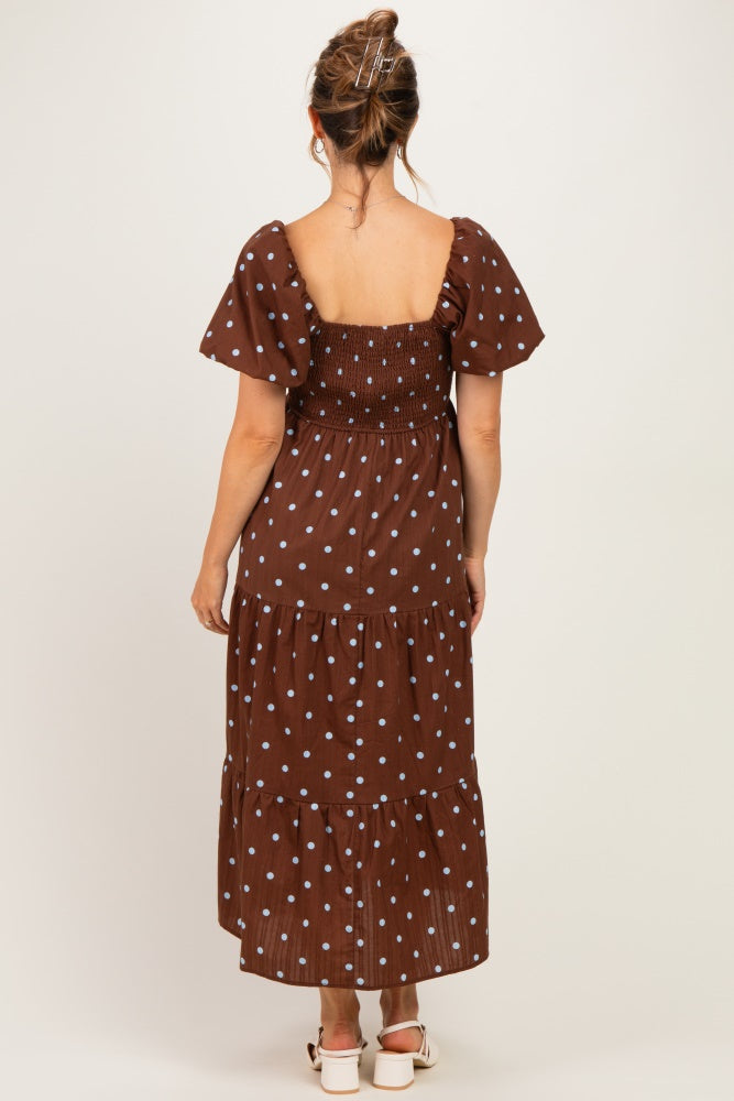 woman wearing a brown polka dot maternity maxi dress with puff sleeves and a tiered skirt, shown from the back