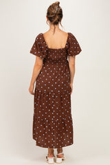 woman wearing a brown polka dot maternity maxi dress with puff sleeves and a tiered skirt, shown from the back