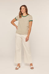 woman wearing a beige and olive green striped t-shirt with green trim and white wide-leg pants